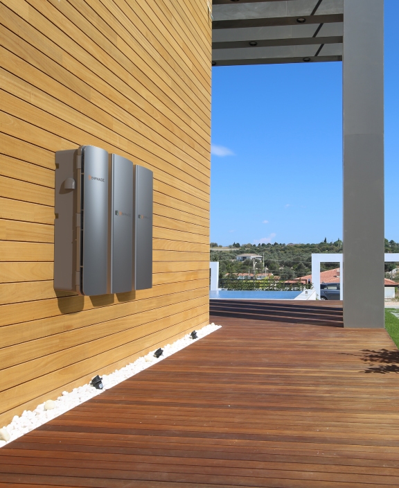 three Enphase batteries installed along exterior wooden wall